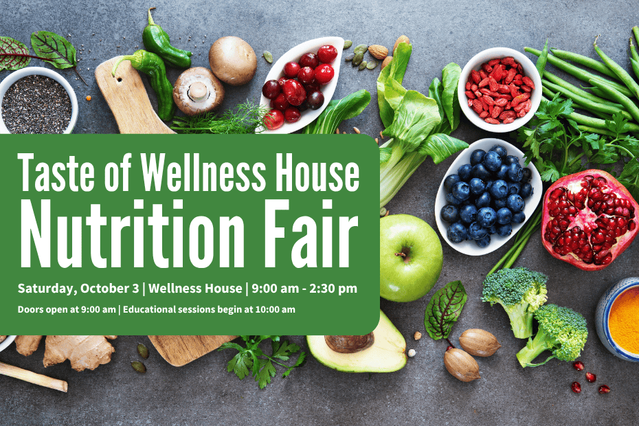 A green sign advertises a nutrition fair, surrounded by fresh fruits, vegetables, nuts, and grains on a light wooden surface.