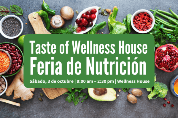 A variety of fresh vegetables, fruit, beans, and seeds surround a green sign for the Taste of Wellness House Feria de Nutrición event with date, time, and location details.